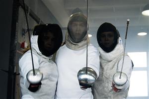 Fencers in protective gear tilt at camera