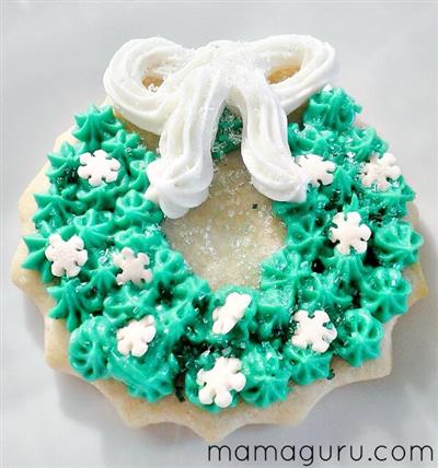 picture of a sugar cookie with green frosting and white snwflaskes in the shape of a wreath