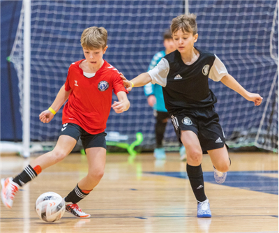 two boys battling for the indoor soccer ball 