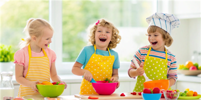picture of 3 happy kids cooking in a bright kitchen with mixing bowls and spoons